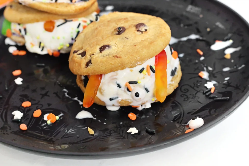 spooky ice cream sandwiches made with chocolate chip cookies, vanilla ice cream, gummy worms, and halloween sprinkles