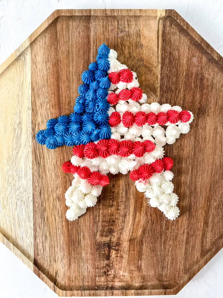 Blue, white, and red piped frosting arranged as a star shape on a wooden cutting board.