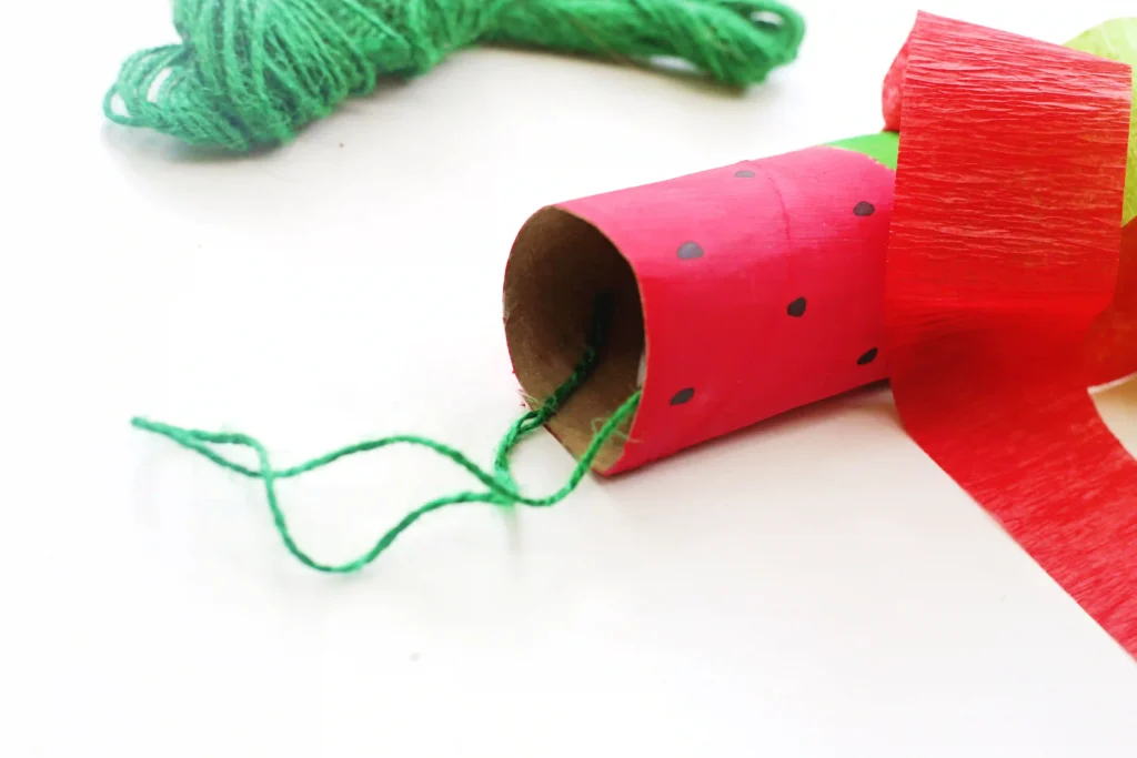 Close-up of a red paper-wrapped cardboard tube with black seeds to look like a watermelon