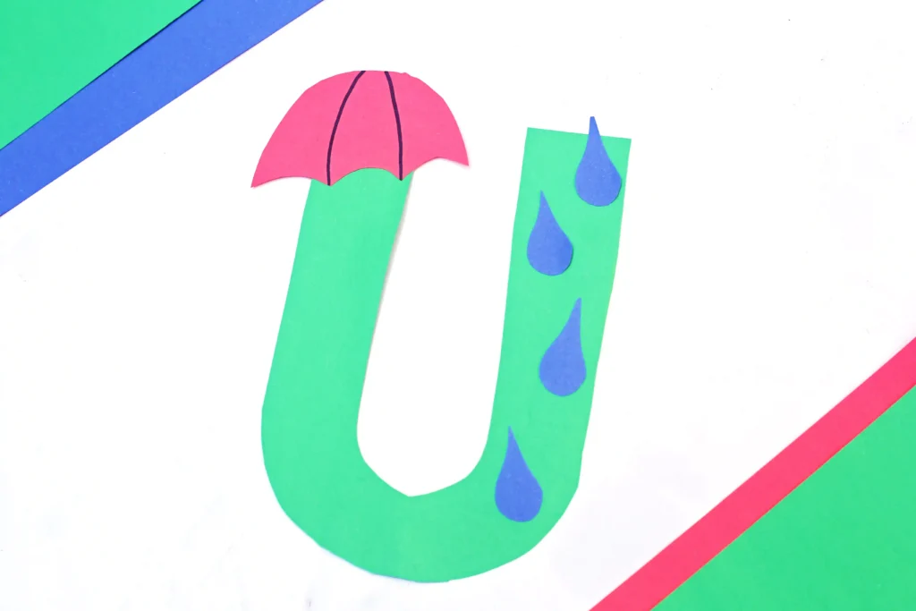 a weather craft for preschoolers of the letter U cut out of green construction paper with an umbrella and rain drops glued on
