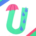 a weather craft for preschoolers of the letter U cut out of green construction paper with an umbrella and rain drops glued on