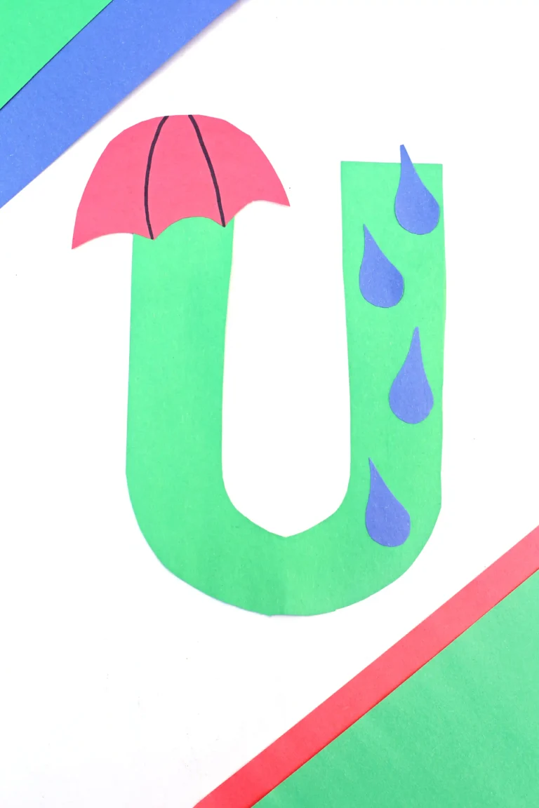 an alphabet craft of the letter U cut out of green construction paper with an umbrella and rain drops glued on