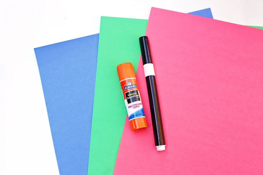 supplies for the letter u craft - red, green, and blue construction paper, a glue stick, and a black marker
