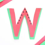 a letter w craft that has a letter w cut out of green and pink construction paper with black seeds drawn on