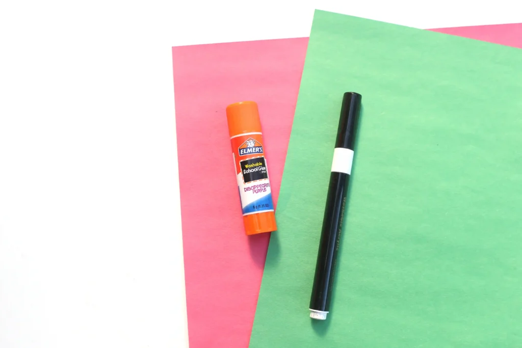 supplies for the w is for watermelon paper craft - pink and green construction paper, a black marker, and a glue stick