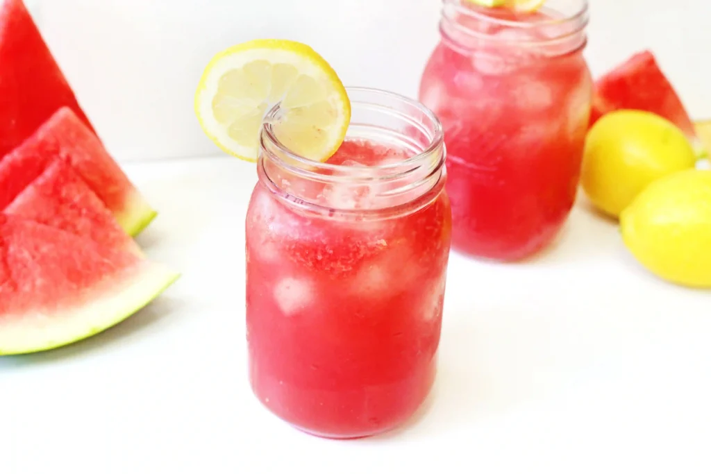 watermelon lemonade with ice and a lemon slice on the edge of the mason jar