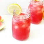 watermelon lemonade with ice and a lemon slice on the edge of the mason jar
