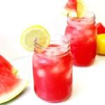watermelon lemonade with ice and a lemon slice on the edge of the mason jar