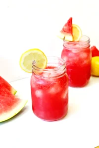 watermelon lemonade with ice and a lemon slice on the edge of the mason jar