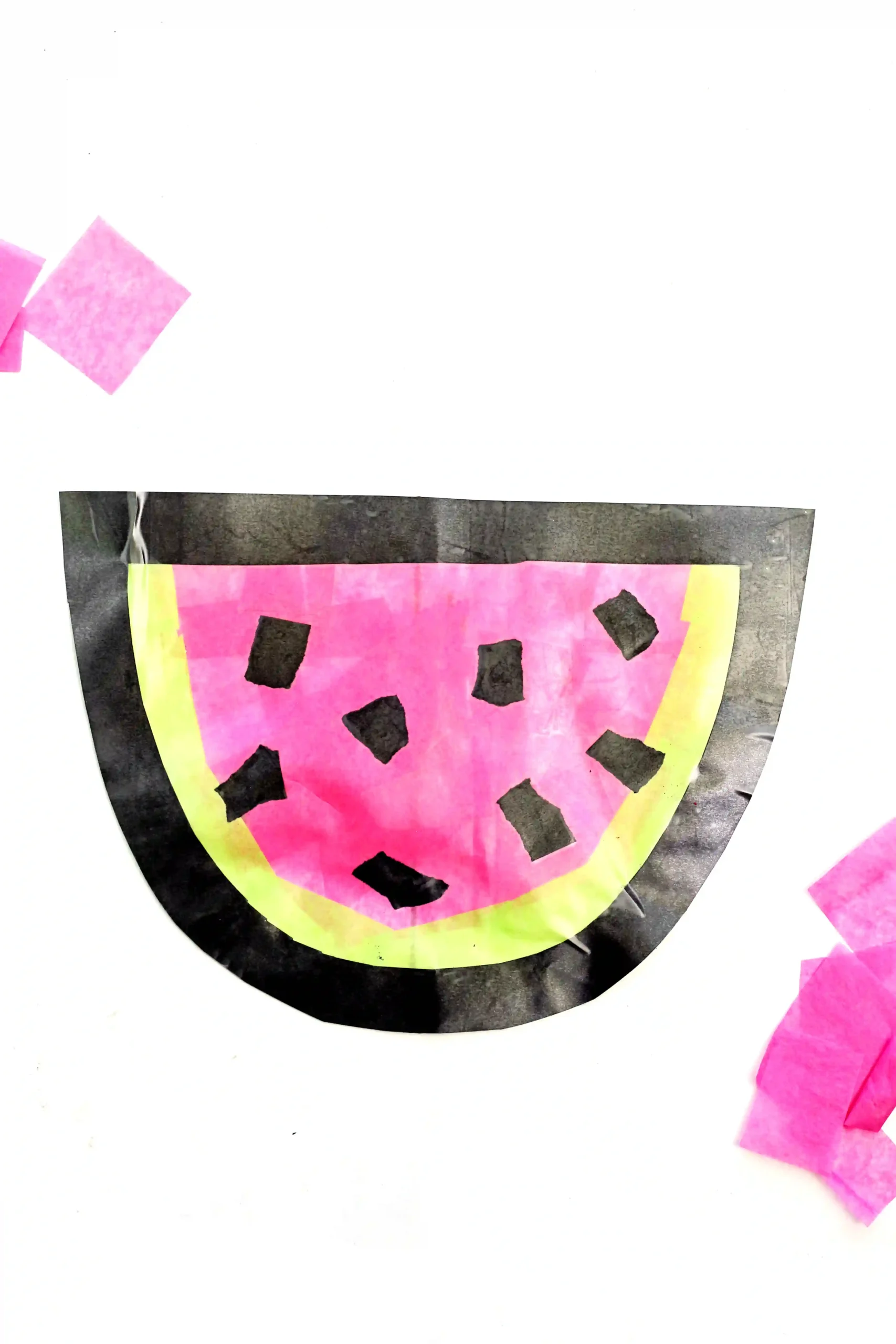 a watermelon suncatcher made of contact paper, construction paper, and tissue paper