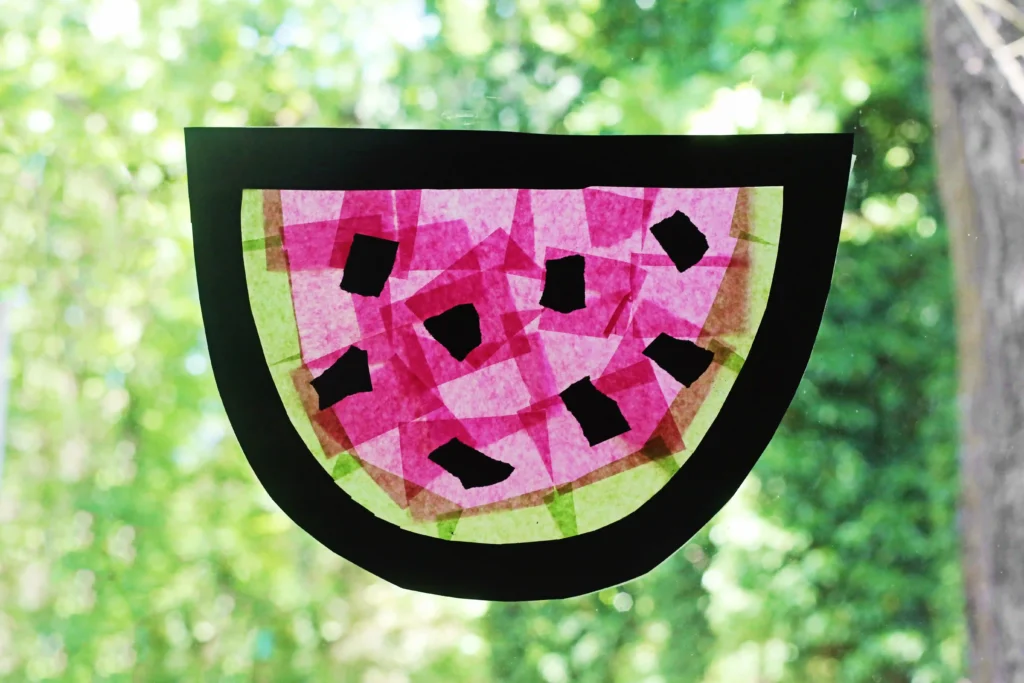 a watermelon suncatcher made of contact paper, construction paper, and tissue paper