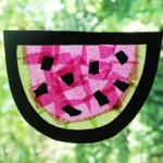 a watermelon suncatcher made of contact paper, construction paper, and tissue paper