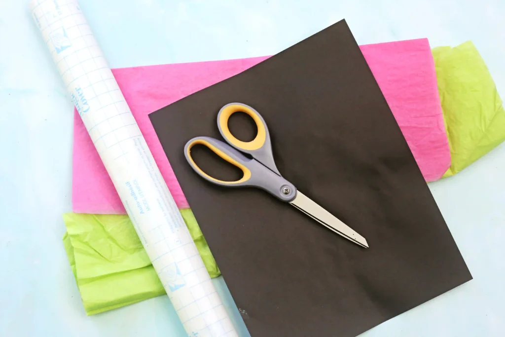 supplies for the watermelon suncatcher- contact paper, black construction paper, pink and green tissue paper, and scissors