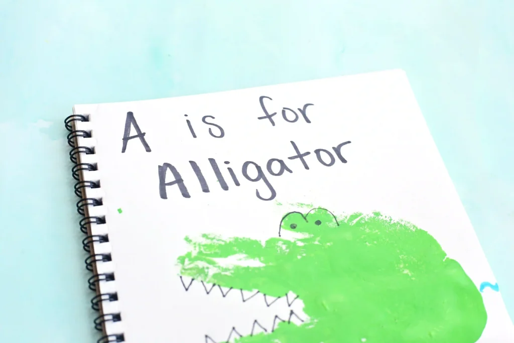 an alligator craft that is a green handprint decorated to look like an alligator in water with writing above it that reads "A is for Alligator"