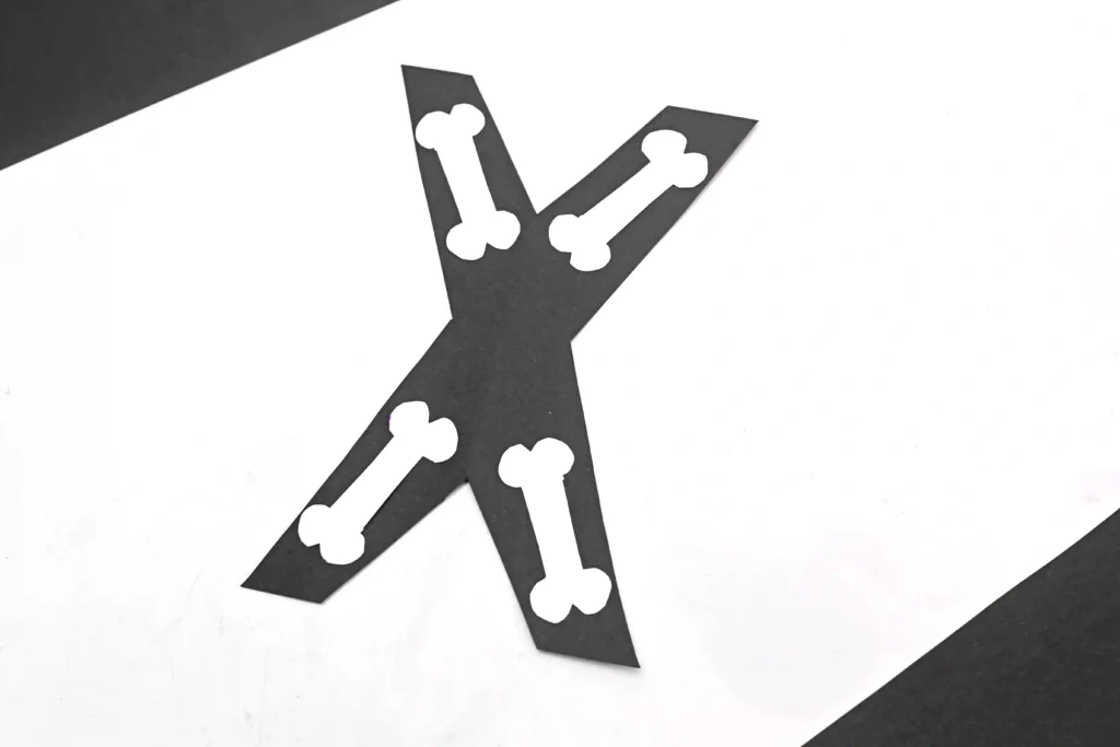 a letter x alphabet craft that has a black x with white bones to look like an x-ray
