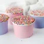dot cakes in a paper cup with nonpareil sprinkles on top