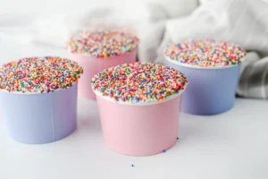 dot cakes in a paper cup with nonpareil sprinkles on top