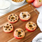 Apple Slice Cookies with peanut butter, chocolate chips, and coconut flakes on a wooden board