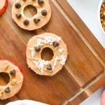 Apple Slice Cookies with peanut butter, chocolate chips, and coconut flakes on a wooden board