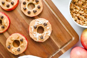 Apple Slice Cookies with peanut butter, chocolate chips, and coconut flakes on a wooden board