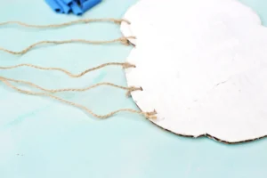 a piece of cardboard cut into the shape of a cloud and painted white with twine tied on for this counting activity for preschool