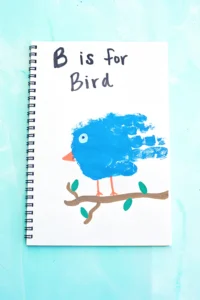 a letter b handprint craft that is a blue handprint with a bead and eye to look like a bird with the words "b is for bird" written above it.