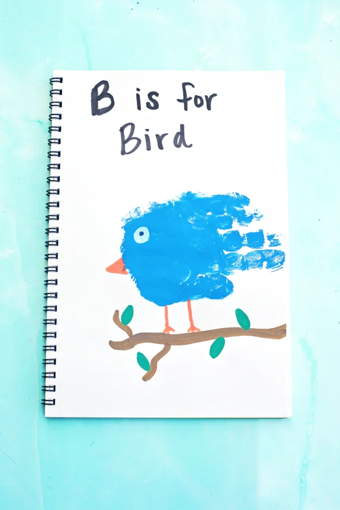 a letter b handprint craft that is a blue handprint with a bead and eye to look like a bird with the words "b is for bird" written above it.