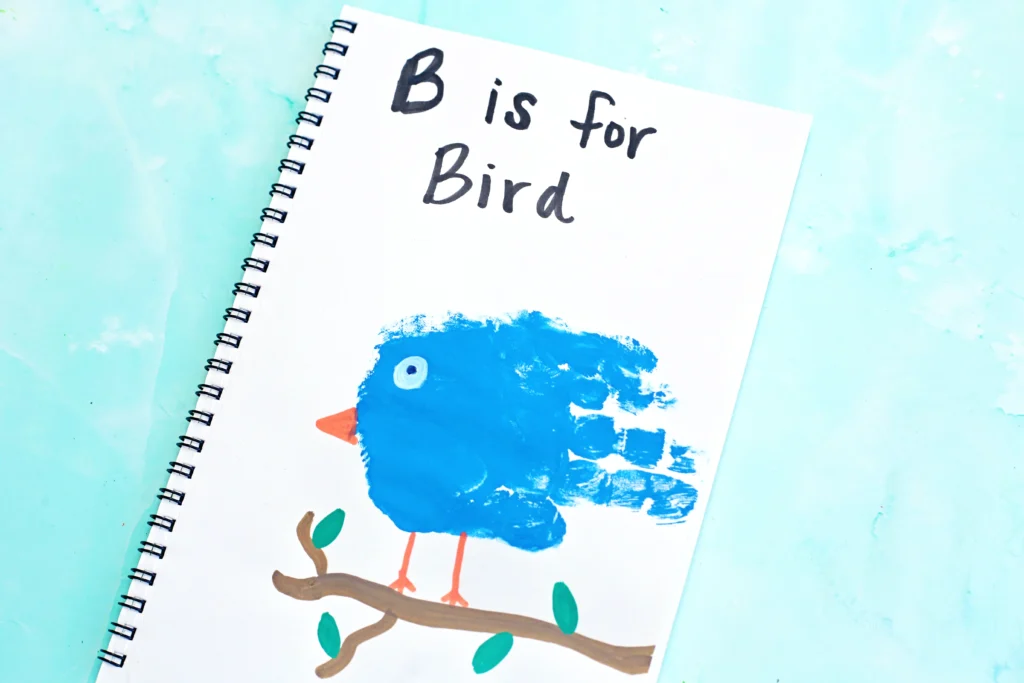 handprint art of a blue handprint with a bead and eye to look like a bird with the words "b is for bird" written above it.
