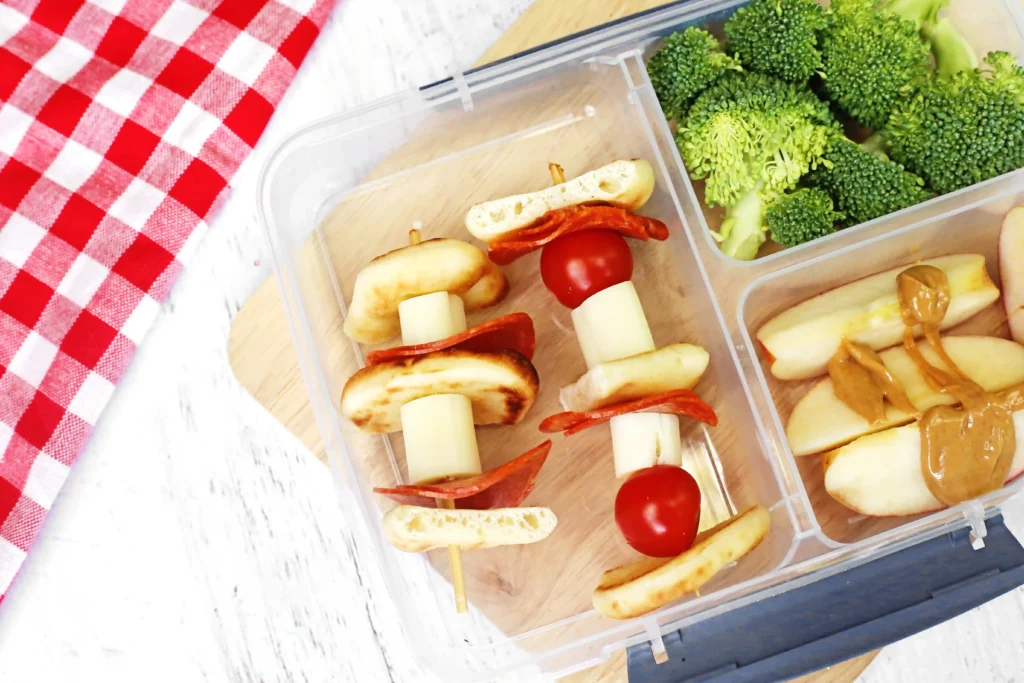 a Backyard Picnic Lunch Idea that has veggie and cheese kabobs, broccoli, and apples with peanut butter