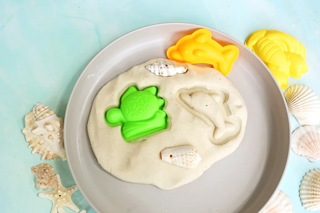 sand playdough recipe with beach toys and shells pressed in