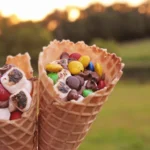 Campfire S'mores Cones that have marshmallows, chocolate chips, and m&ms in a waffle cone