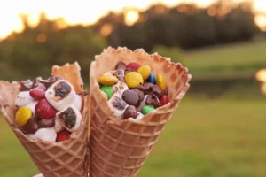 Campfire S'mores Cones that have marshmallows, chocolate chips, and m&ms in a waffle cone