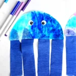 a Coffee Filter Jellyfish Craft with a coffee filter colored iwth blue, pink, and purple markers and blue streamers for the jellyfish tentacles