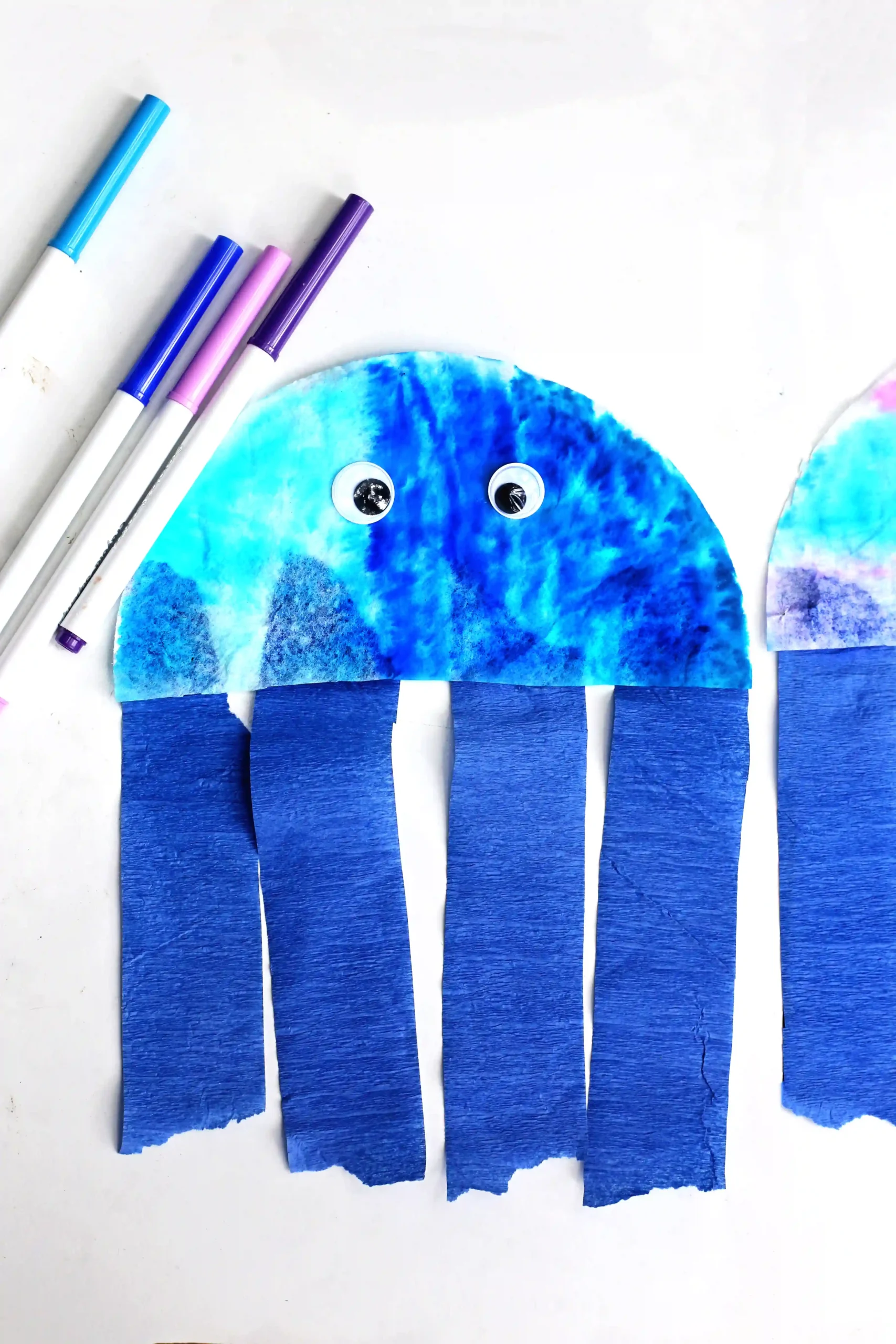 Coffee Filter Jellyfish Craft - Cultivating Brilliant Minds a Coffee Filter Jellyfish Craft with a coffee filter colored iwth blue, pink, and purple markers and blue streamers for the jellyfish tentacles