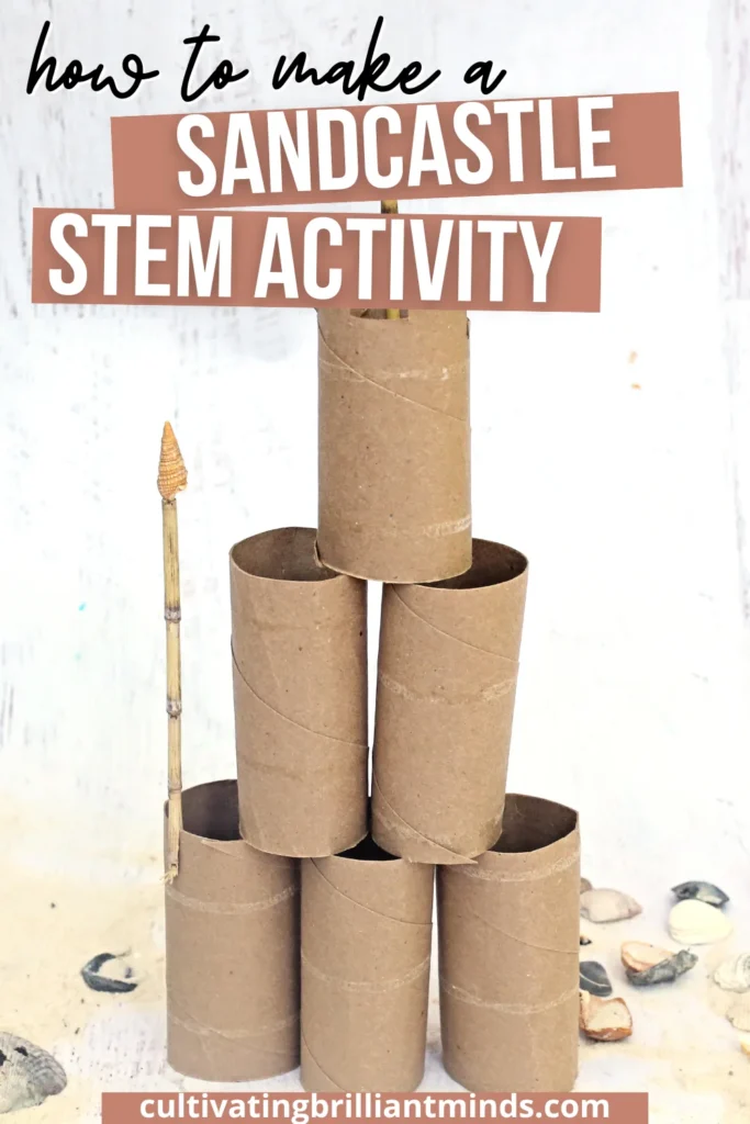 Towering sandcastle built from stacked cardboard toilet-paper tubes, with a small shell perched on a vertical stick at the top, on a light surface with seashells nearby