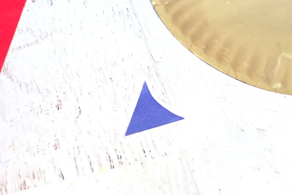 Close-up of a marbled surface featuring a blue triangle with partial red and gold shapes nearby on a white textured background.