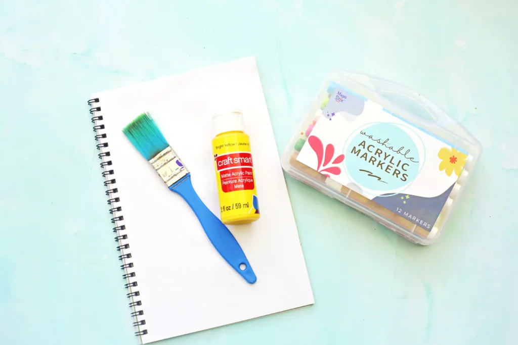 Letter D Duck Handprint Craft - Cultivating Brilliant Minds supplies for the Letter D handprint craft - notebook, paintbrush, yellow paint, and markers