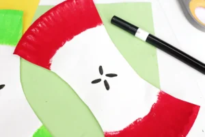 an Apple Core Paper Plate Craft that has a paper plate cut and painted to look like an apple core with seeds