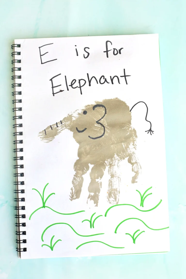 Notebook page with handwritten 'E is for Elephant' and a brown elephant stamp/paint, surrounded by green vine doodles.