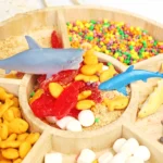 Blue shark-shaped toy rests on a display of colorful candies in wooden crates.