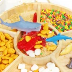 an Edible Shark Bait Sensory Bin with goldfish crackers, nerds, swedish fish, marshmallows, and toy sharks