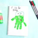 a letter f handprint craft that is a green handprint decorated to look like a frog