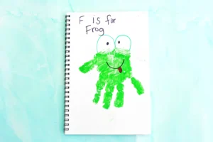 Notebook page with a green frog illustration and the text "F is for Frog" on a light blue background.
