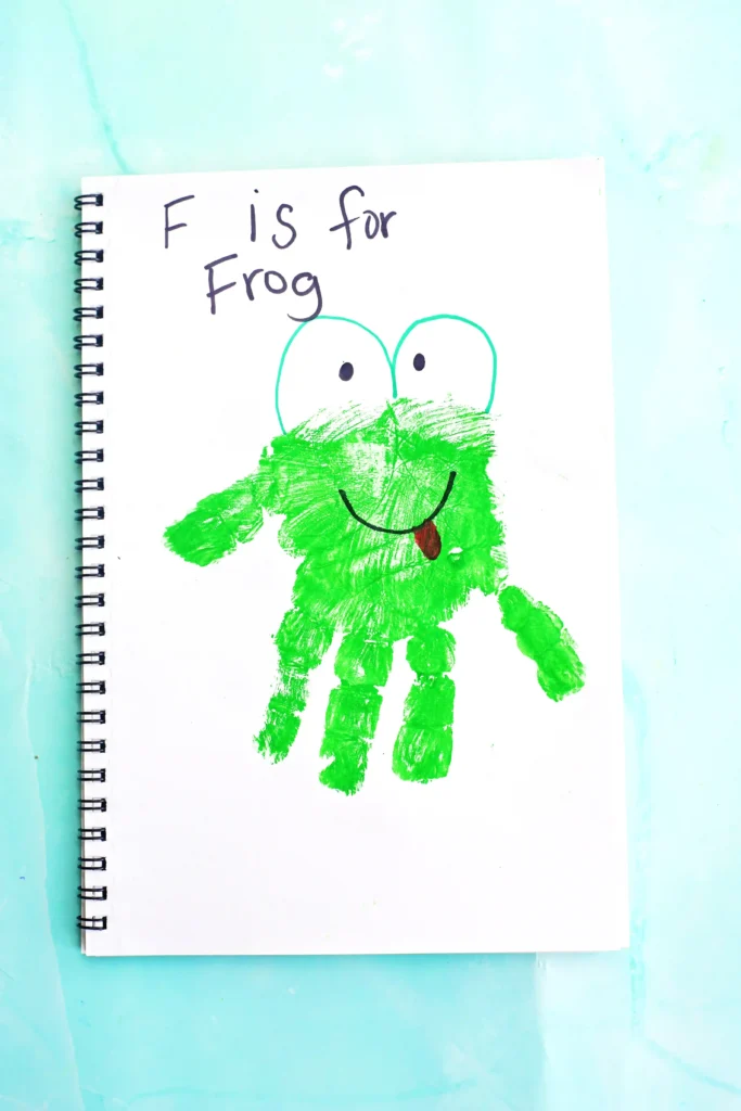 Letter F Frog Handprint Craft - Cultivating Brilliant Minds Notebook page with a green frog drawing and the words'F is for Frog'.
