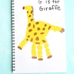 a letter g handprint craft that is a yellow handprint decorated to look like a giraffe with words "G is for giraffe"