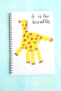 a letter g handprint craft that is a yellow handprint decorated to look like a giraffe with words "G is for giraffe"