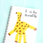 a letter g handprint craft that is a yellow handprint decorated to look like a giraffe with words "G is for giraffe"