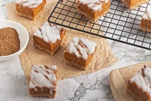 pumpkin pie bars on parchment paper with some on a black cooling rack in the background