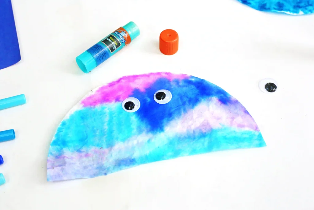Coffee Filter Jellyfish Craft - Cultivating Brilliant Minds a coffee filter that has been cut in half and colored with markers with googly eyes glued on to look like a jellyfish for this ocean craft