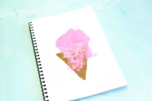 White spiral notebook with a pink paint handprint on a brown triangle to look like an ice cream cone